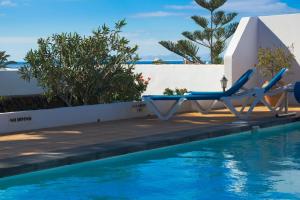 a pool with a lounge chair next to a swimming pool at Villa Corona in Puerto del Carmen