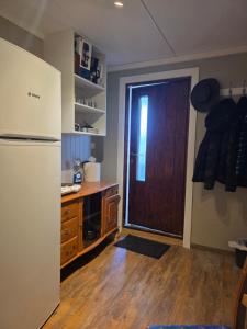 a kitchen with a refrigerator and a wooden door at Fjord & Fjell Idyll in Tunheim
