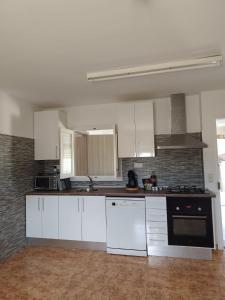 a kitchen with white cabinets and a stove top oven at La Caseta Dels Avis in Sant Jaume d'Enveja