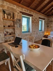 a kitchen with a table with a bowl of fruit on it at Light & Stone Villa, Kefalonia in Lixouri +17 photos