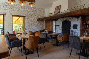 a dining room with tables and chairs and a stone wall at La Maison des Ocres - Provence in Roussillon