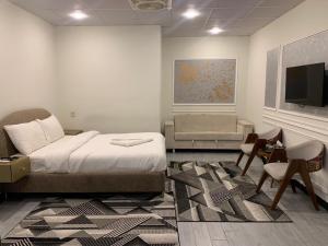 a bedroom with a bed and a tv and a chair at Luxvill Hotel in Islamabad +42 photos