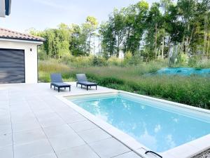a swimming pool with two chairs next to a patio at Maison Peyrelade in Coulounieix-Chamiers