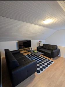 a living room with two black leather couches and a rug at 13min boxen, Legoland43min, MCH10min in Herning