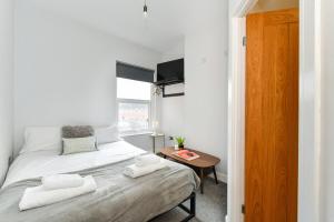 a white bedroom with a bed and a table at Long Eaton Modern 4bed House in Long Eaton +25 photos