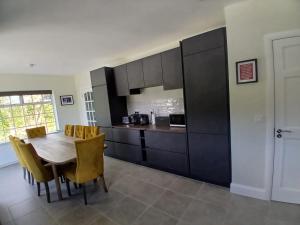 a kitchen with a wooden table and yellow chairs at The Coast House in Kilmore