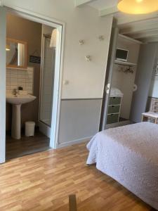 a bedroom with a bed and a bathroom with a sink at "Les Charmilles" - Maison de charme dans un ancien cloître in Sailly-Flibeaucourt