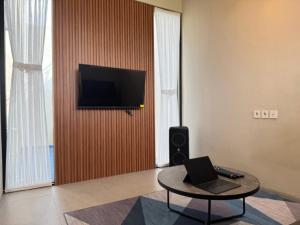 a living room with a table and a television on a wall at Villa Grand Metro in Batu