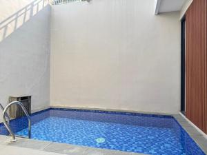 a swimming pool with blue tiles in a building at Villa Grand Metro in Batu