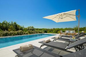 a group of lounge chairs and an umbrella next to a swimming pool at Villa Modrić by IstriaLux in Trviž