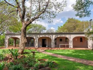 an old building with a tree in the yard at Nyala Lodge in Rayton