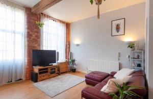 a living room with a couch and a flat screen tv at Raleigh Loft in Nottingham