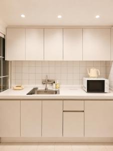 a kitchen with white cabinets and a microwave at Coco Villa Sinsa in Seoul