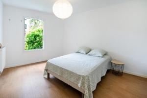 a white bedroom with a bed and a window at Appartement proche du port in Capbreton