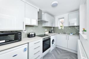 a white kitchen with white cabinets and a dishwasher at Newark Central Cottage in Newark-on-Trent