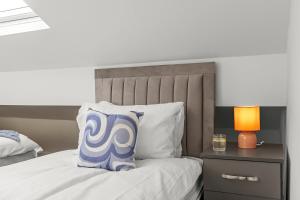 a bed with a blue and white pillow on it at Stylish & Spacious Home in the Heart of Leeds in Central Station +7 photos
