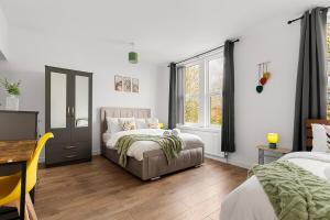 a bedroom with two beds and a table and a window at Stylish & Spacious Home in the Heart of Leeds in Central Station