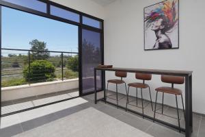 a bar with stools in a room with a window at taira suite in Rosh Pinna