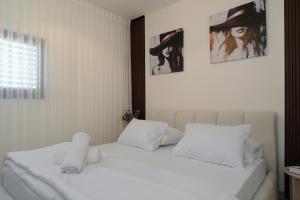 a bedroom with a white bed with three pictures on the wall at taira suite in Rosh Pinna