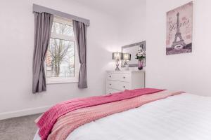 a white bedroom with a bed and a window at Hope Street in Filey