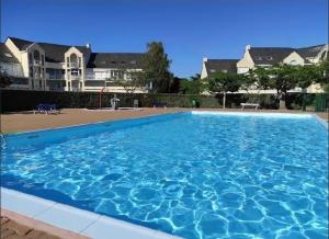 a large blue swimming pool with houses in the background at Ti Mad, Echappée belle à La Baule - mer et piscine in Guérande