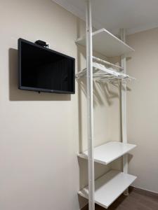 a room with a tv on a wall with shelves at PENSIÓN ISBEL in Málaga +1 photo