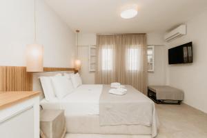 una camera da letto con un letto bianco e una televisione di TRINITY THE HOTEL ad Ammouliani