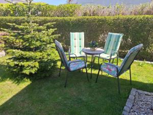 three chairs and a table in the grass at Zum Rosengarten in Rambin +3 photos