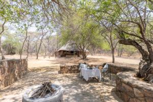 a table and a hut in the middle of a field at Palala River Cottages in Vaalwater