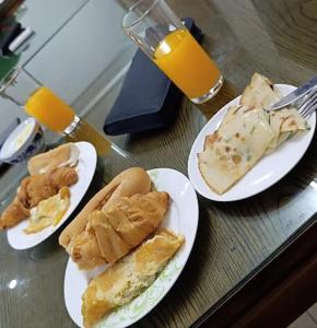 three plates of food on a table with orange juice at Hotel Nana in Abidjan