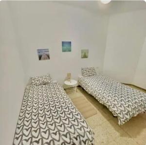 two beds in a room with a white wall at Barbate Beach Apartment in Barbate