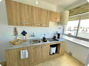 a kitchen with wooden cabinets and a sink and a window at Barbate Beach Apartment in Barbate