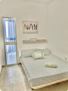 a white bedroom with a bed and a window at Barbate Beach Apartment in Barbate