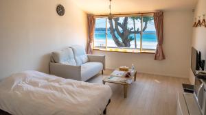 a bedroom with a bed and a chair and a window at Beach Front Seretis in Shimoda