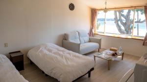 a bedroom with a bed and a chair and a table at Beach Front Seretis in Shimoda