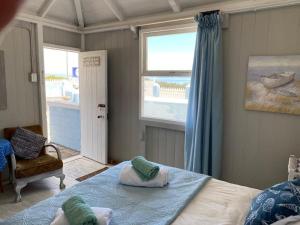 a bedroom with a bed and a window with a view of the ocean at Port Nolloth Beach Shack in Port Nolloth