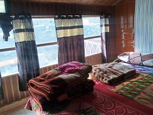 a bedroom with two beds and a large window at Himalayan siddhi yog aashram in Badrinath