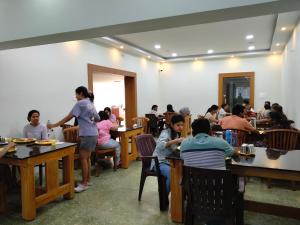 a group of people sitting at tables in a restaurant at Richmount Natural Resort Pvt Ltd in Yercaud