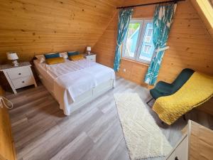 a bedroom with a bed and a chair in a room at Domki w Jarzębinach - Domek z widokiem in Piechowice