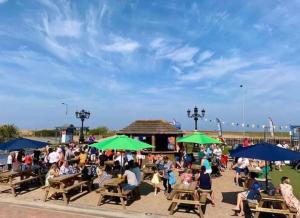 a group of people sitting at tables under green umbrellas at Unique 2 bed lodge lyons Robinhood in Rhyl
