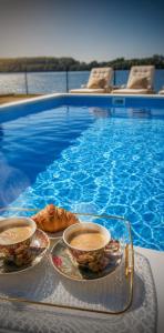 two cups of coffee on a tray next to a swimming pool at Kucica na Dunavu in Smederevo