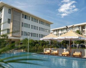 a swimming pool with umbrellas and chairs and a hotel at THE NAVY HOUSE HOTEL in Sattahip