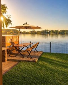 a picnic table with an umbrella and chairs next to a lake at Kucica na Dunavu in Smederevo