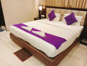 a large bed with purple and white sheets and pillows at Hotel Radiant in Kolkata