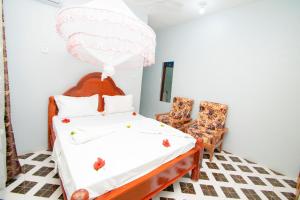 a bedroom with a bed and two chairs at Kigwedeni Apartments in Kinyasini