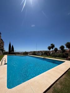 a swimming pool with blue water and palm trees at Ónice de Riviera 2 in Mijas Costa