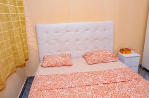 ein weißes Bett mit zwei Kissen darauf in der Unterkunft Residence Mobagnes in Kinshasa