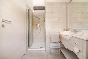 a white bathroom with a sink and a shower at B&B La Casa di Pamela - 5 min Lago Varese in Varese