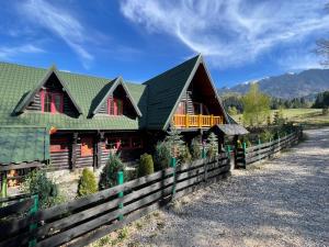a house with a green roof and a fence at Dolce Cabana in Timisul de Jos