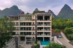 a building with a pool and mountains in the background at Yangshuo Gallery Resort--River View, Sunset,Cafe,Karast Mount,Ten-Mile Gallery,Free Laundry,Travel Guide,Book Tickets in Advance,E-Scooter Service in Yangshuo